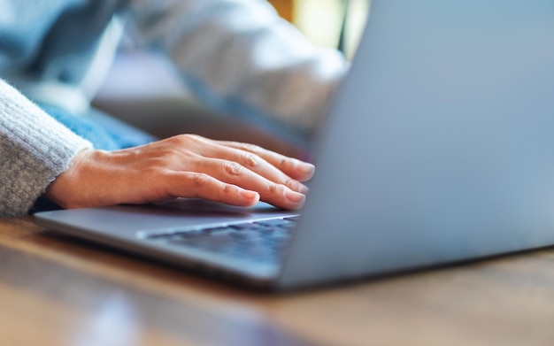 Imagem aproximada de uma mulher trabalhando e tocando no touchpad do laptop em cima da mesa