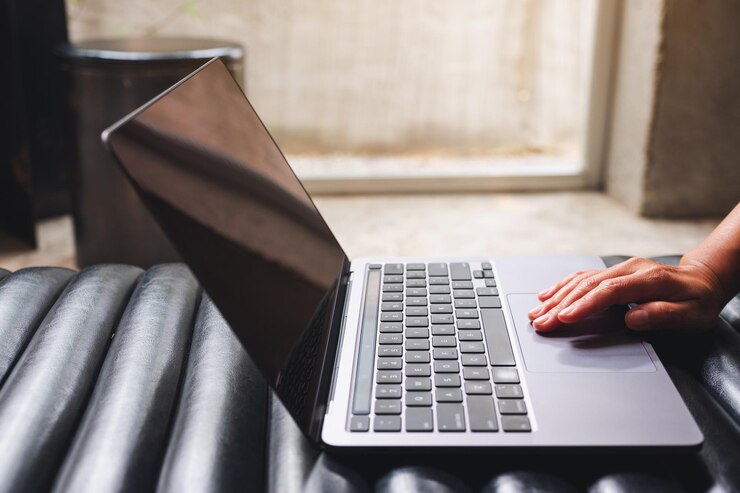 Foto imagem aproximada de uma mulher trabalhando e tocando no touchpad do laptop em cima da mesa