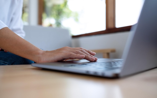 Imagem aproximada de uma mulher trabalhando e tocando o touchpad do laptop na mesa