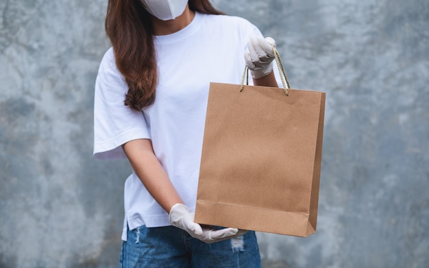 Imagem aproximada de uma mulher usando máscara facial protetora e luvas médicas de borracha entregando sacola de compras para o cliente Cuidados de saúde e conceito Covid19