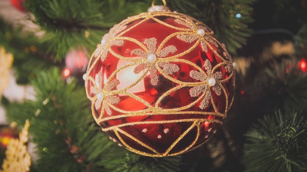 Imagem aproximada de vermelho com bugiganga de ouro pendurada na árvore de Natal