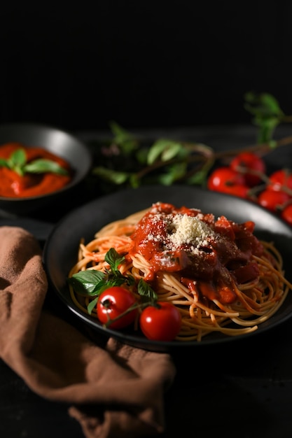 Imagem aproximada Deliciosa massa italiana Tomate Spaghetti com fundo escuro desfocado da mesa de jantar