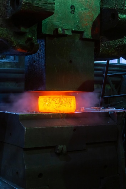 Imagem aproximada do processo de forjamento manual de aço quente com grande máquina de martelo mecânico