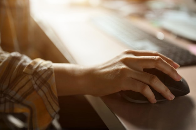 Imagem aproximada Mão feminina usando um mouse de computador sem fio em sua mesa de escritório