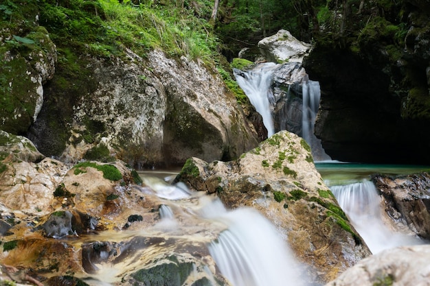 Imagem borrada de belo fluxo de água correndo sobre cascatas e pequenas cachoeiras na natureza verde do verão