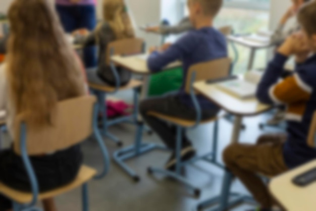 Foto imagem borrada de crianças em idade escolar sentadas na sala de aula no fundo da lição de volta à escola