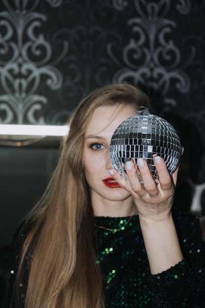 Imagem chique de festa de boate de véspera de ano novo de linda garota em vestido de noite brilhante com bola de discoteca