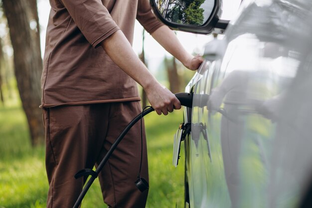 Imagem colorida da mão de um homem se preparando para carregar um carro elétrico