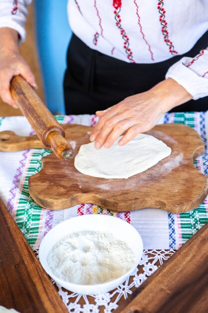 imagem com as mãos de uma senhora cozinhando as tradicionais tortas fritas romenas com queijo