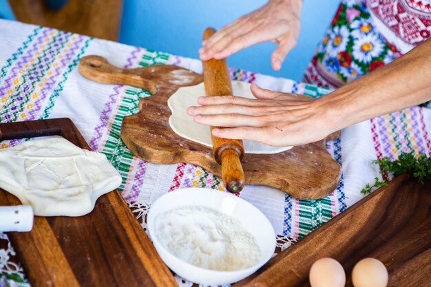 imagem com as mãos de uma senhora cozinhando as tradicionais tortas fritas romenas com queijo