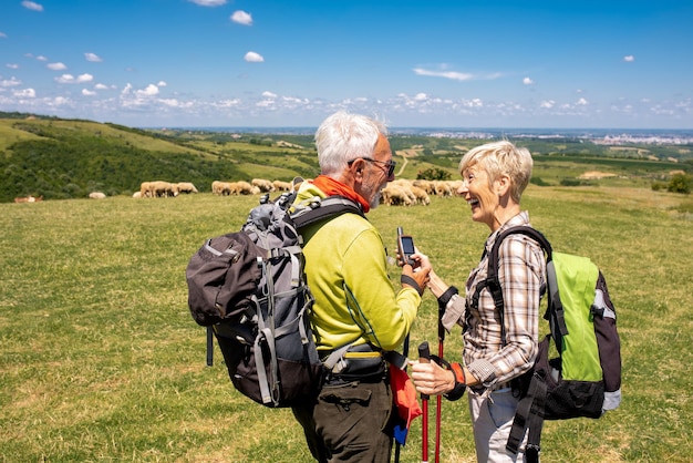 Foto imagem com foco superficial de um casal de idosos usando uma bússola elétrica em um grande campo