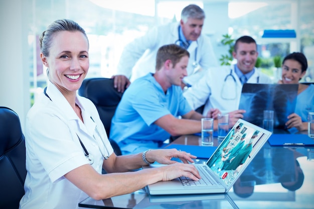 Imagem composta da bela médica sorridente digitando no teclado com sua equipe atrás