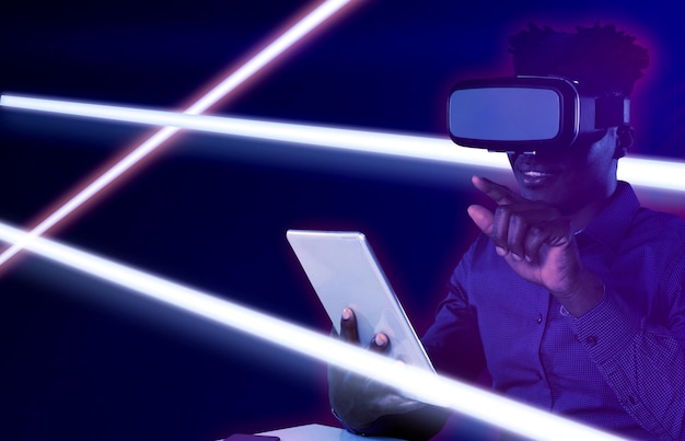 Imagem composta de afro-americano masculino usando fone de ouvido de realidade virtual e tablet digital