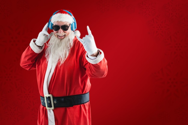 Imagem composta de alegre papai noel mostrando sinal de mão enquanto ouve música em fones de ouvido