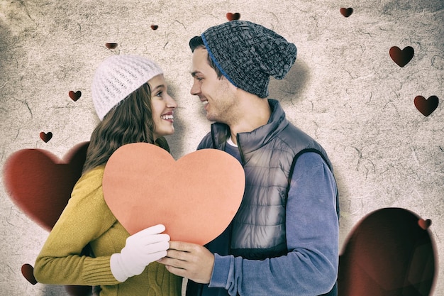 Imagem composta de casal feliz segurando coração de papel