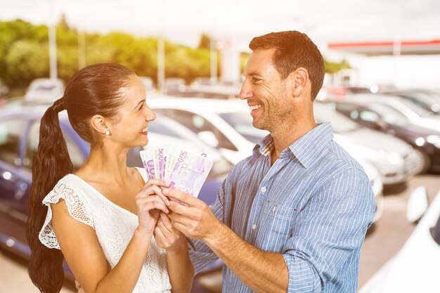 Imagem composta de casal sorridente segurando dinheiro