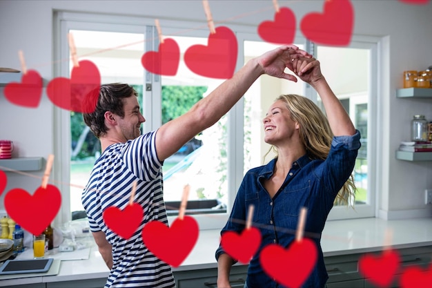 Foto imagem composta de corações vermelhos pendurados e casal dançando na cozinha