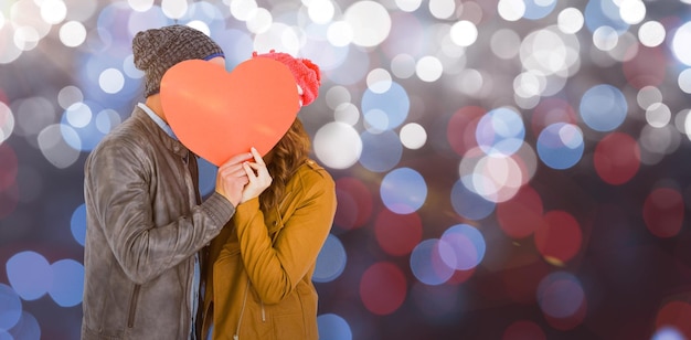 Imagem composta de feliz casal jovem segurando papel em forma de coração