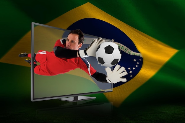 Imagem composta de goleiro em forma salvando gol pela tv contra bandeira brasileira acenando