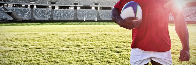 Imagem composta de jogador de rugby masculino segurando uma bola de rugby no chão