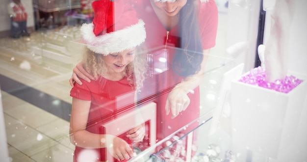 Imagem composta de mãe e filha em trajes de natal, olhando para o visor do relógio de pulso