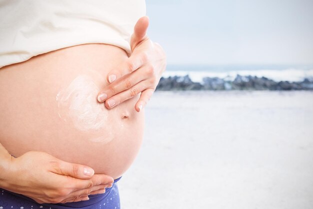 Imagem composta de mulher grávida com creme na barriga