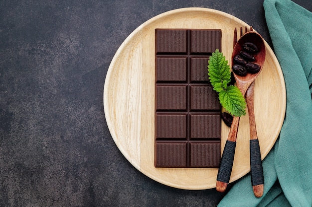 Imagem conceitual de comida com chocolate escuro e garfo no fundo escuro de concreto.