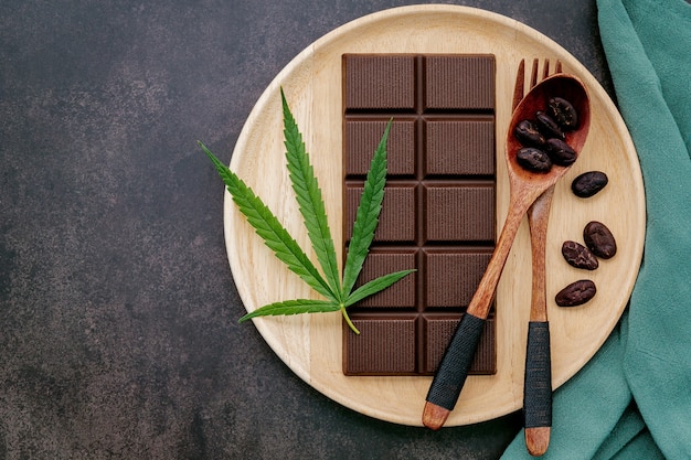 Imagem conceitual de comida de folha de cannabis com chocolate escuro e um garfo no concreto escuro.