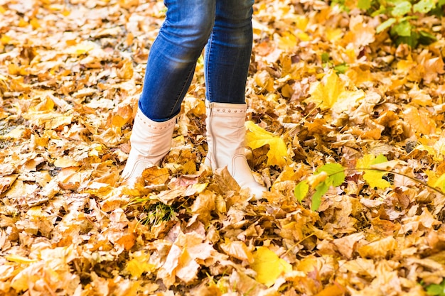 Imagem conceitual de pernas em botas nas folhas de outono. sapatos de pés caminhando na natureza.