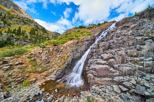 Imagem da cachoeira sobre rochas pontiagudas nas coloridas montanhas de outono