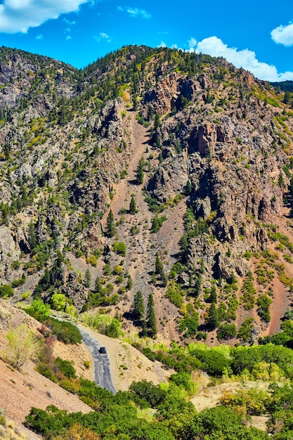 Imagem da estrada com carro no fundo de um grande desfiladeiro e vista de penhascos de montanha