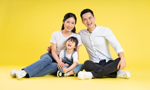 Imagem da família asiática sentada feliz e isolada em fundo amarelo