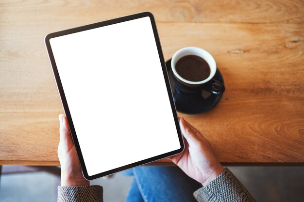 Imagem da maquete de vista superior de uma mulher segurando um tablet pc preto com uma tela branca em branco