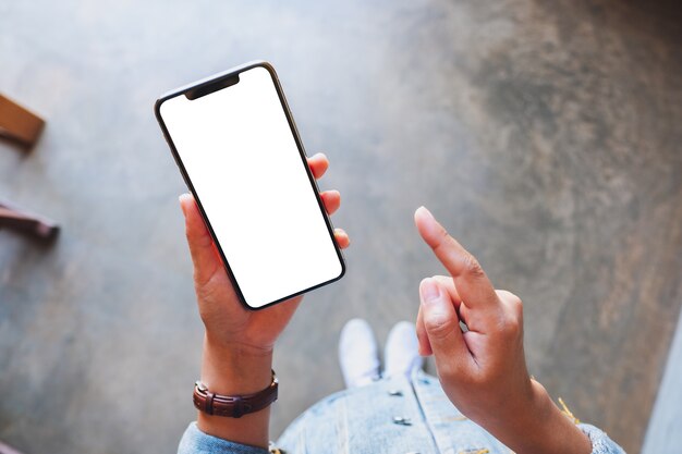 Imagem da maquete de vista superior de uma mulher segurando um telefone celular preto com uma tela branca em branco