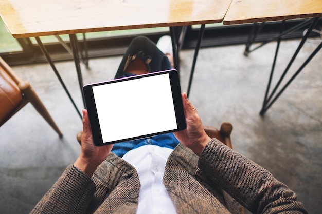 Imagem da maquete de vista superior de uma mulher sentada e segurando um tablet pc preto com uma tela em branco