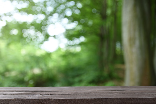 Imagem da mesa de madeira cinza na frente de árvores natureof turva abstratas em um prado verde