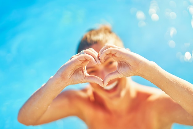 Imagem da mulher na piscina mostrando o coração com as mãos
