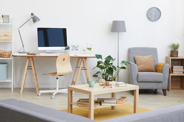 Imagem da sala de estar com local de trabalho, monitor de computador e outros móveis modernos da casa