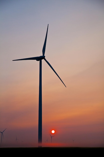 Imagem da silhueta do moinho de vento contra as laranjas de um sol poente