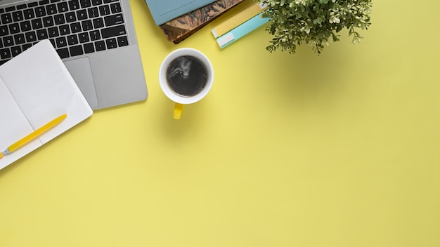 Imagem da vista superior da mesa de trabalho colorida com acessórios colocando sobre ela. apartamento leigos computador portátil com tela em branco branca, caneta, caneta marcador, caderno, diário, xícara de café e vasos de plantas.