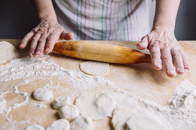 Imagem das mãos de duas mulheres fazendo bolinho de carne com rolo de madeira