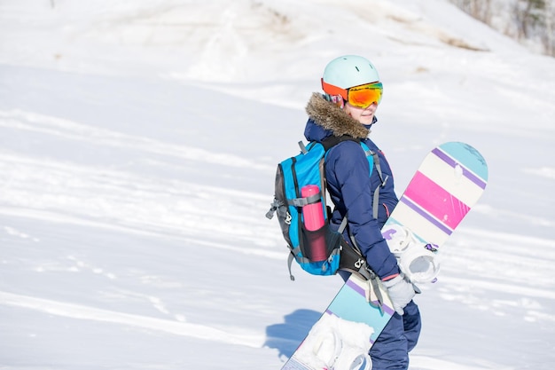 Imagem de atleta feminina usando capacete com mochila e snowboard