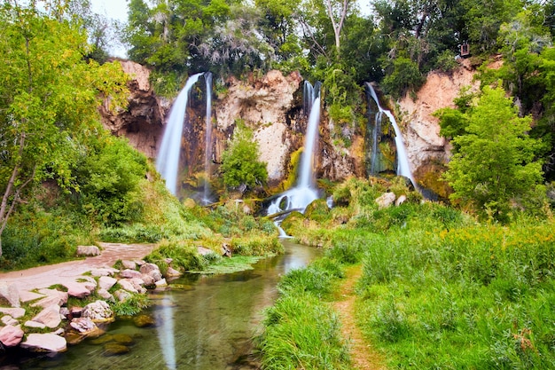 Imagem de belas cachoeiras triplas em uma floresta exuberante com uma trilha simples e um rio