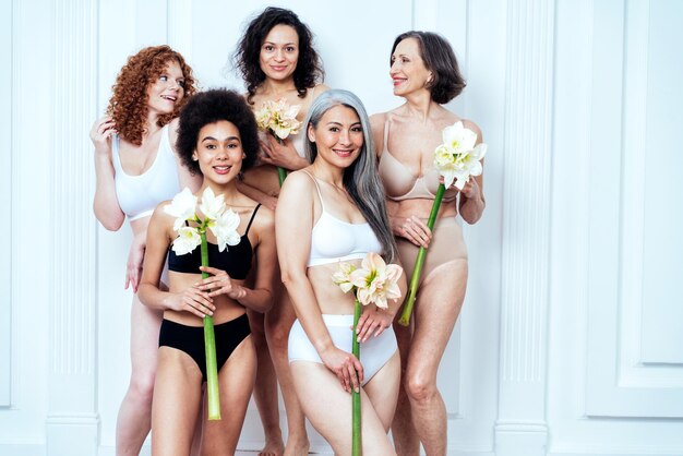 Foto imagem de beleza de um grupo de mulheres com diferentes idades, pele e corpo posando em estúdio para um ensaio fotográfico positivo. modelos femininos mistos em lingerie em fundos coloridos