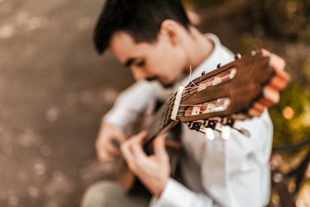 Foto imagem de blured do músico masculino que joga a guitarra acuostic ao ar livre. vista de alto ângulo.