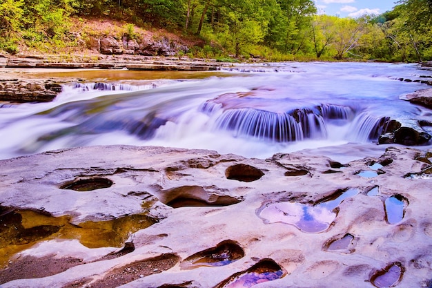 Imagem de cachoeira com superfície rochosa cheia de buracos