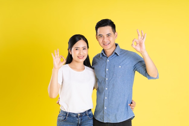 Imagem de casal asiático posando em fundo amarelo