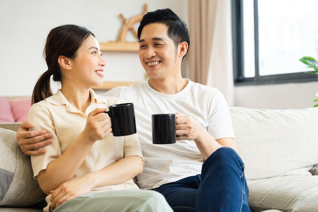 Imagem de casal asiático sentado no sofá em casa