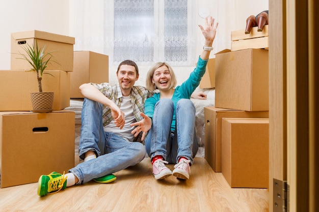 Imagem de casal feliz sentado no sofá entre caixas de papelão