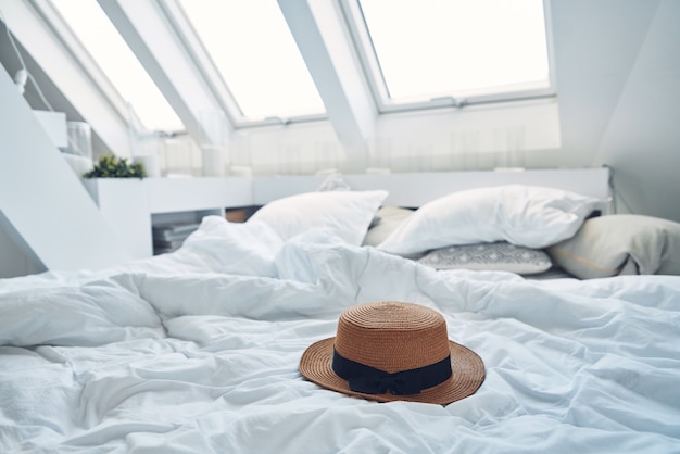 Imagem de chapéu deitado na cama com travesseiros e babá ao redor